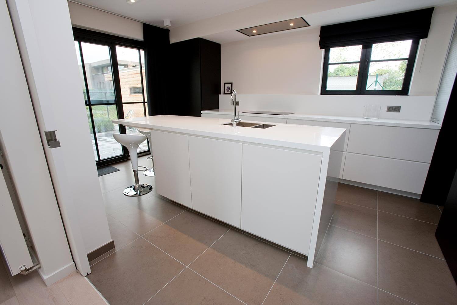 foto van moderne witte keuken met grote, grijze, keramische tegels en zwarte accentmuren