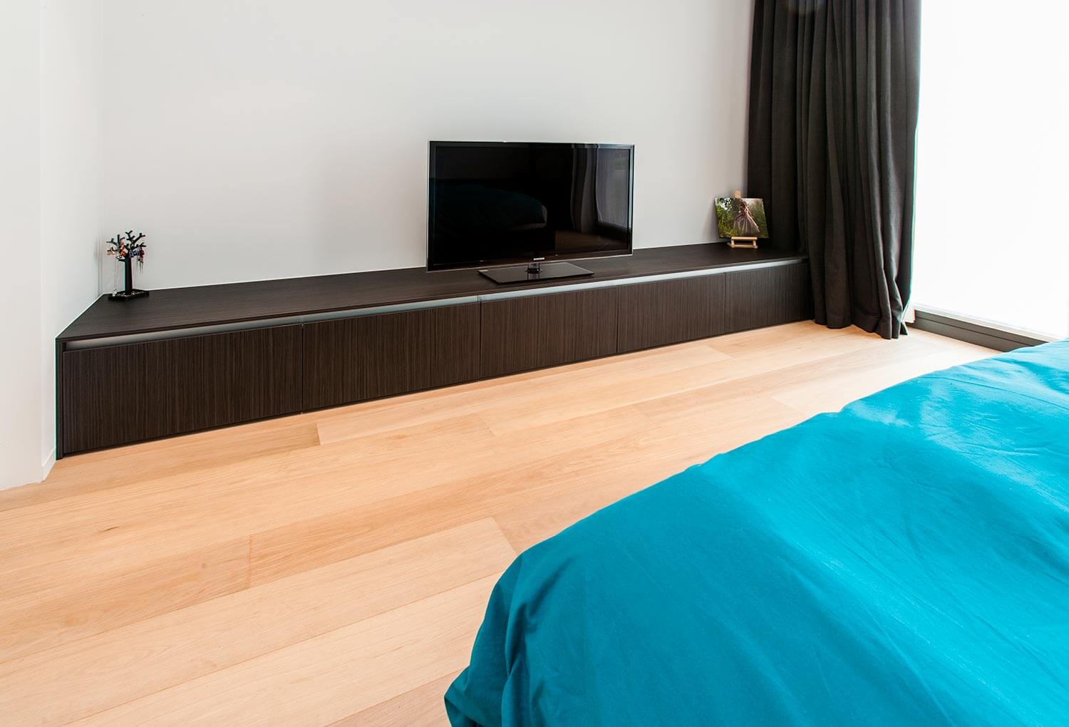 foto van de slaapkamer met een op maat gemaakt tv-meubel, over de gehele breedte dat vlak tegen de grond staat