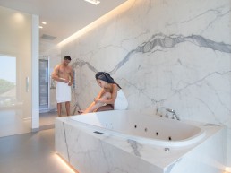 foto van koppel in een moderne badkamer met keramische tegels die de indruk van marmer geven.
