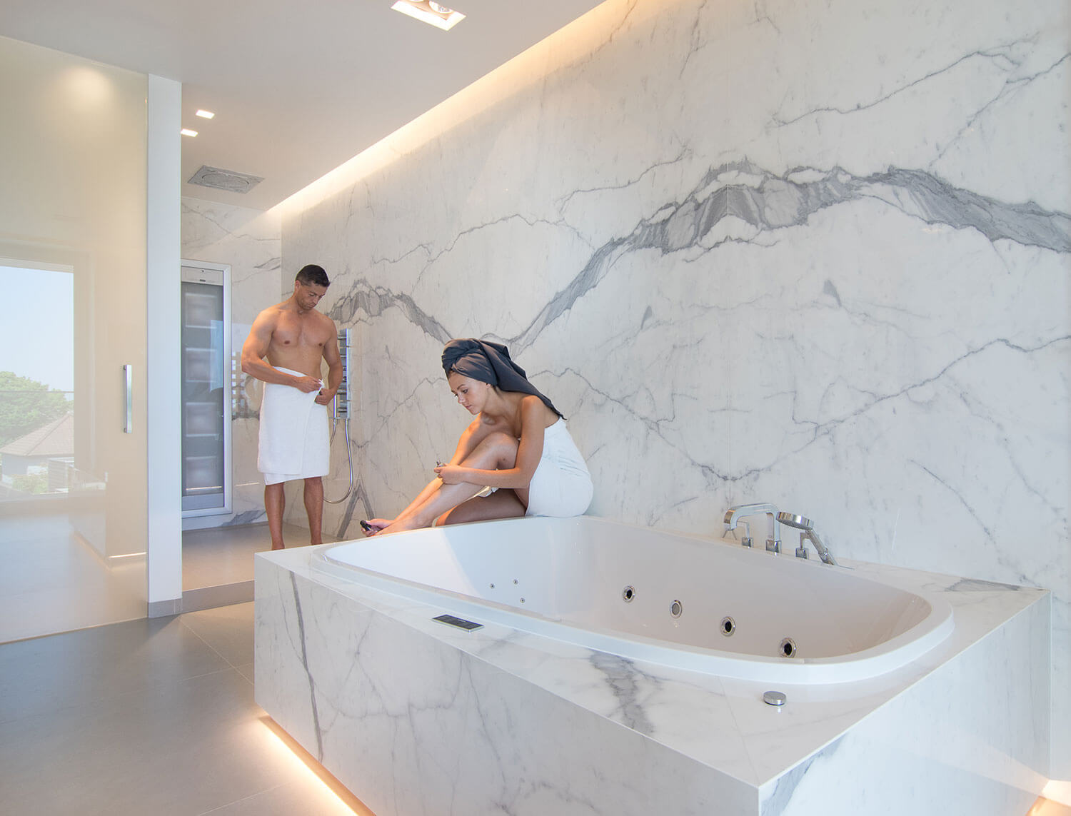 foto van koppel in een moderne badkamer met keramische tegels die de indruk van marmer geven.