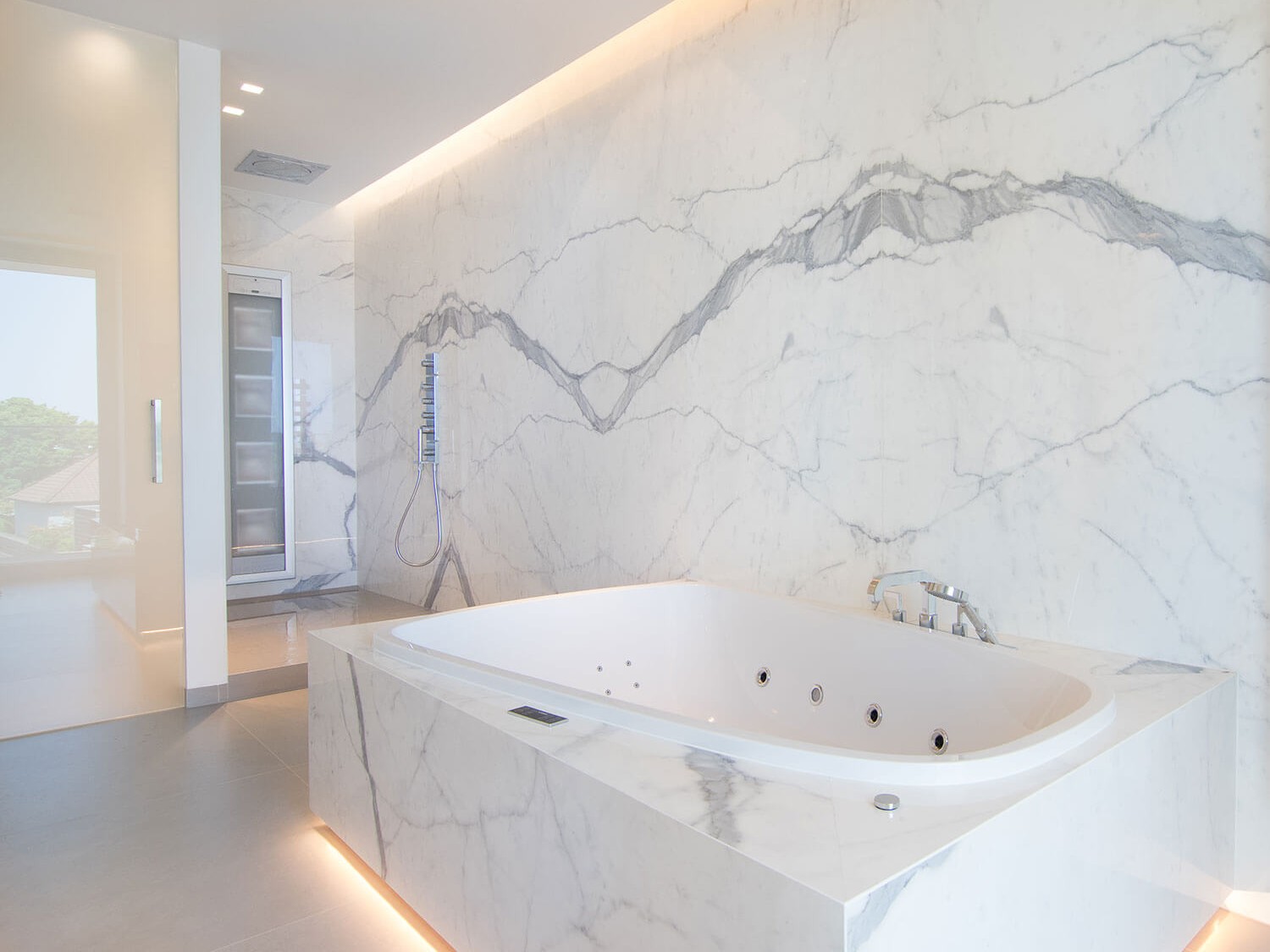 foto van bad en douche in moderne badkamer met keramische tegels die de indruk van marmer geven