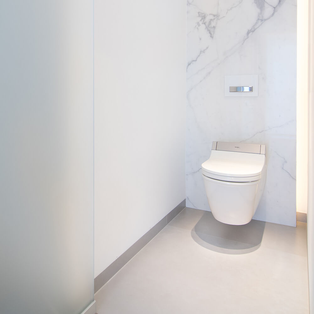 foto van hangtoilet in moderne badkamer met keramische tegels die de indruk van marmer geven
