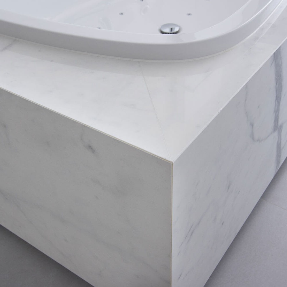 Detailfoto van bad in moderne badkamer met keramische tegels die de indruk van marmer geven