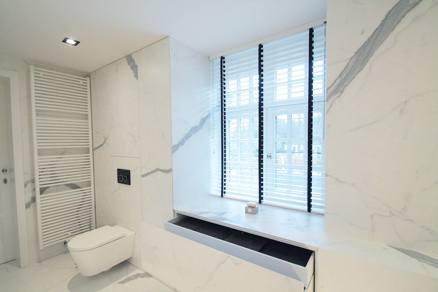 foto van moderne badkamer, foto van de hoek met het hangtoilet. op de muur en grond werden keramische grootformaat tegels gebruikt met een marmer effect