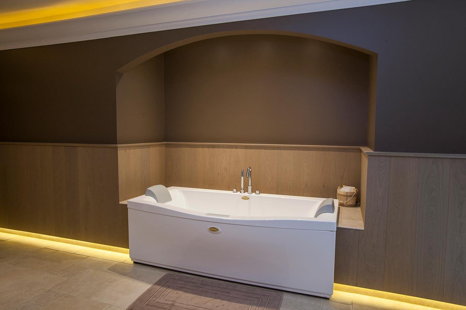 foto van bad in Wellness-ruimte. bruin geverfde muren, houten lambrisering en op de vloer beige, keramische tegels